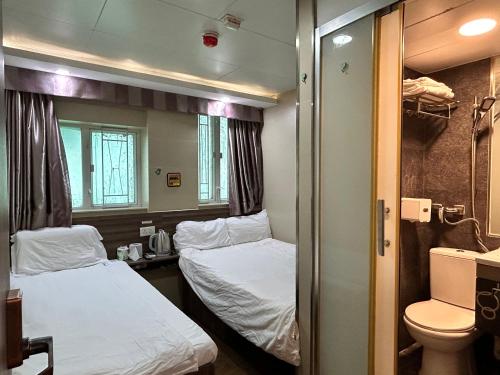 Cette petite chambre comprend 2 lits et des toilettes. dans l'établissement 香港星星旅馆 b&b, à Hong Kong