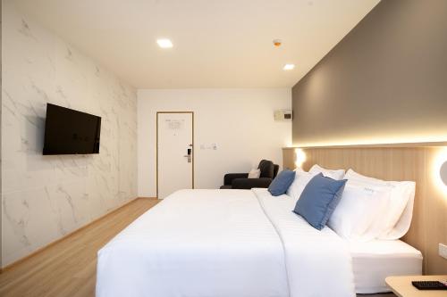 a bedroom with a large white bed with blue pillows at Diya Hotel Bangkok in Amphoe Phra Khanong