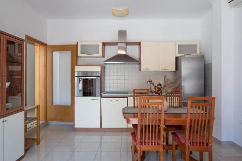 kuchnia ze stołem, krzesłami i lodówką w obiekcie Apartments K & N w mieście Prižba