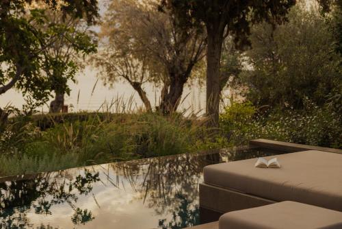 a pool with a table and chairs next to a body of water at Minos Beach Art Hotel, a Member of Design Hotels in Agios Nikolaos