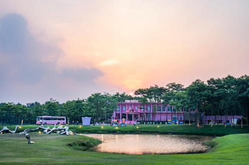 a large pink building with a pond in front of it at Rosee Villa - Green Villa with private Pool in Vĩnh Phúc