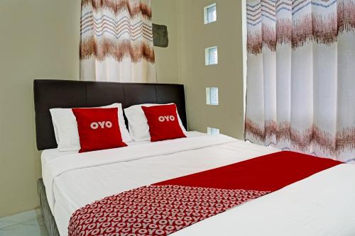 a bedroom with a large bed with red pillows at OYO 91707 Jannah Homestay Syariah in Dau