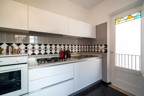una cocina con armarios blancos y fregadero en Al Duomo Rooms & Flats en Taormina