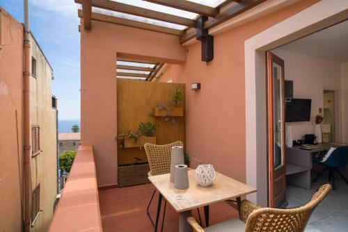 een klein balkon met een houten tafel en stoelen bij Al Duomo Rooms & Flats in Taormina