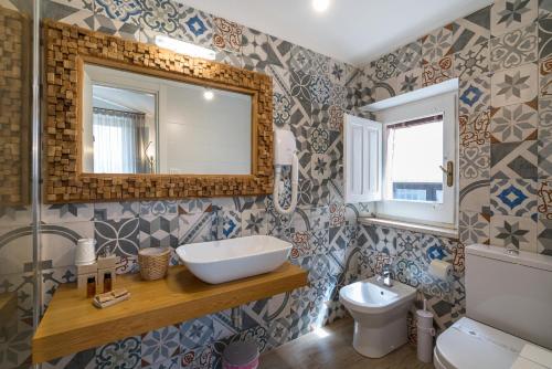 a bathroom with a sink and a toilet and a mirror at Al Duomo Rooms & Flats in Taormina