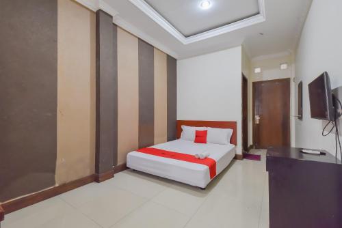 ein Schlafzimmer mit einem Bett und einem TV in der Unterkunft RedDoorz near Universitas Maranatha Bandung in Bandung