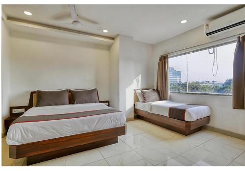 a bedroom with two beds and a window at Kanchan Tilak in Indore