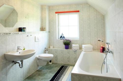 a bathroom with a sink and a toilet and a tub at Cottages at the Kummerower See, Verchen in Verchen