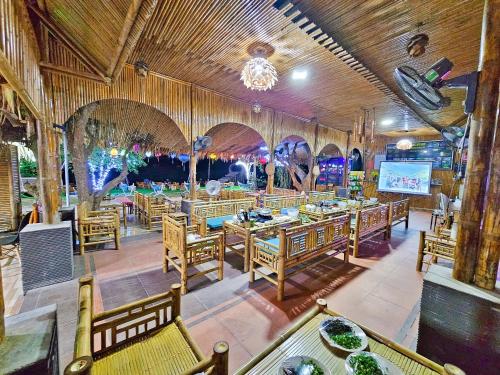 a restaurant with wooden tables and chairs and a screen at Quoc Khanh Bamboo Homestay in Ninh Binh
