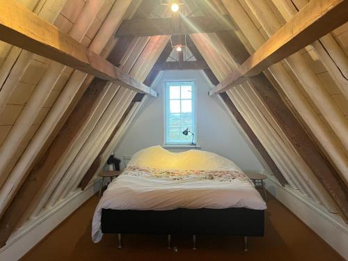 ein kleines Schlafzimmer mit einem Bett im Dachgeschoss in der Unterkunft Cozy home with a view on the harbour in Brielle