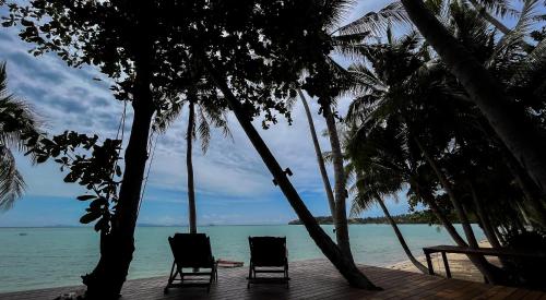 two chairs sitting on a wooden deck next to the ocean at Private Beach House @ Hin Kong Beach in Hinkong