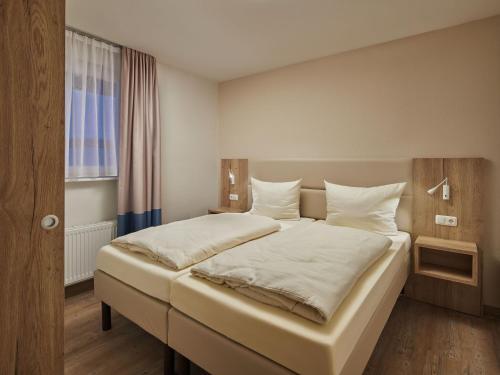una camera da letto con un letto con lenzuola bianche e una finestra di Apartments im Ferien- und Freizeitpark Weissenhäuser Strand, Weissenhäuser Strand a Weissenhäuser Strand