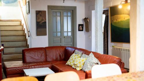 a living room with a brown leather couch with pillows at Casa Rural La Chocolateria in Horche