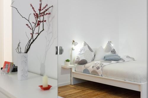 a bedroom with white walls and a bed with a vase at Wichertstraße 47 in Berlin