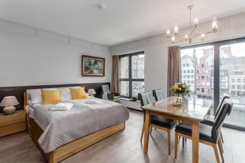 a bedroom with a bed and a table with chairs at Apartamenty Premium - kompleks Deo Plaza in Gdańsk