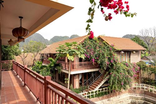 a house with a balcony with flowers on it at Tam Coc Ngoc Linh Bungalow Ninh Bình in Ninh Binh