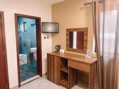 a bathroom with a sink and a mirror at Sky Suites-Byblos Hotel Osu in Accra