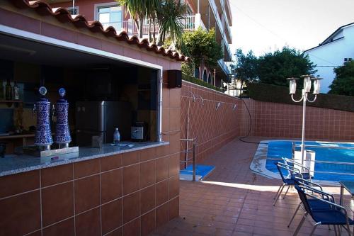 a building with a swimming pool and a patio with chairs at Hotel Las Vegas in Cangas de Morrazo