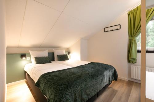 1 dormitorio con 1 cama grande con sábanas verdes en Summio Bungalowpark Het Hart van Drenthe, en Zwiggelte