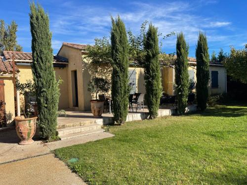 a row of cypress trees in front of a house at Villa proche d'Avignon. in Le Pontet
