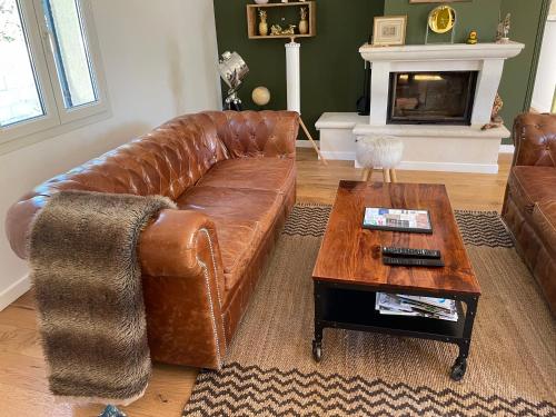 a living room with a brown leather couch and a coffee table at Villa proche d'Avignon. in Le Pontet