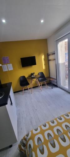 een kamer met een tafel en twee stoelen en een televisie bij Studio Jasmin avec jardin, rénové in Saint-Quentin