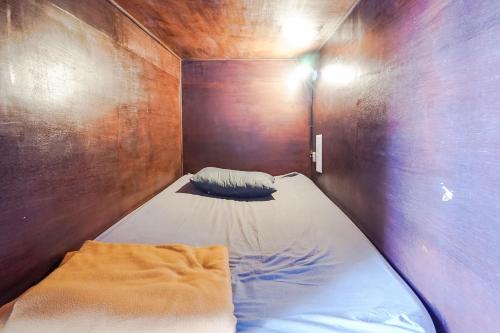 Piccola camera con letto su una parete in legno. di Bali Backpacker Inn & Hostel ad Ubud