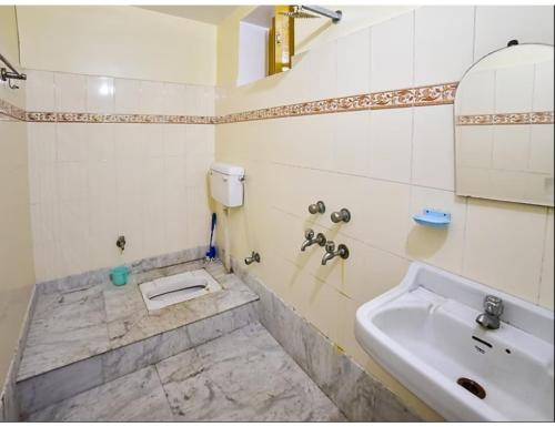 ein Badezimmer mit einem Waschbecken, einem WC und einem Spiegel in der Unterkunft Shivam Guest House, Gaya in Gaya