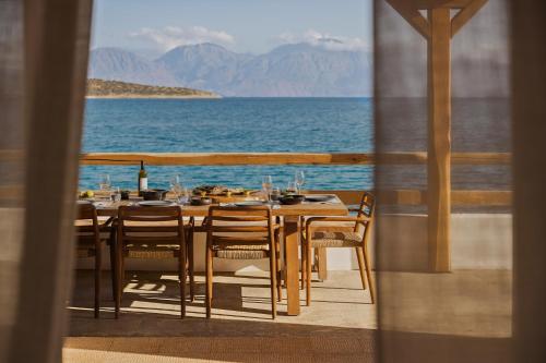 a table with chairs and a view of the ocean at Minos Beach Art Hotel, a Member of Design Hotels in Agios Nikolaos