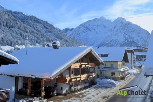 a building covered in snow with mountains in the background at Alp-Chalet in Hirschegg