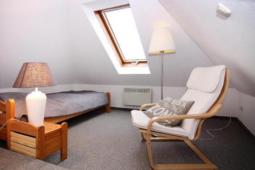 a attic room with a bed and a chair and a lamp at Holiday complex Wenkendorf, Fehmarn-Wenkendorf in Lemkendorf
