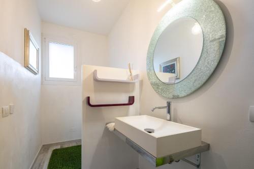 a white bathroom with a sink and a mirror at Villino Aurora by VacaVilla in Ciggiano