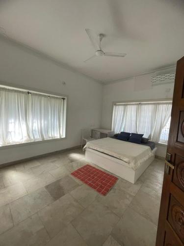 a white bedroom with a bed and two windows at Flyon HomeStay in Kannur
