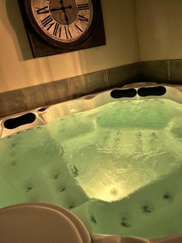 a large bath tub with a clock on the wall at Just'un Instant in Landrecies