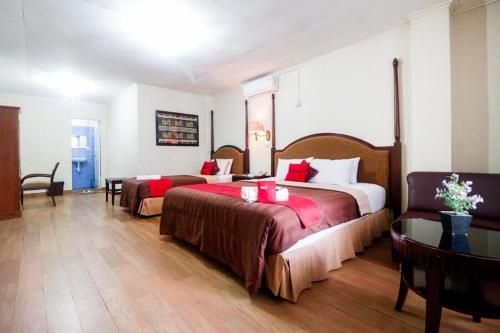 a hotel room with two beds and a table at RedDoorz Plus @ Jalan Raden Intan Lampung in Bandar Lampung