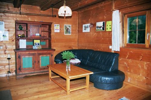 a living room with a black leather couch and a table at Bischofhütten in Bad Sankt Leonhard im Lavanttal