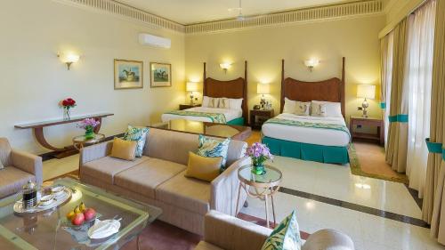a hotel room with two beds and a living room at Ramgarh Lodge, Jaipur – IHCL SeleQtions in Jaipur