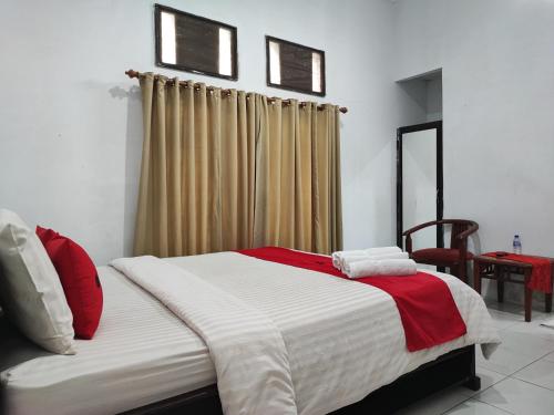 Schlafzimmer mit einem Bett mit roter und weißer Bettwäsche in der Unterkunft RedDoorz Syariah near Universitas Batanghari Jambi in Jambi