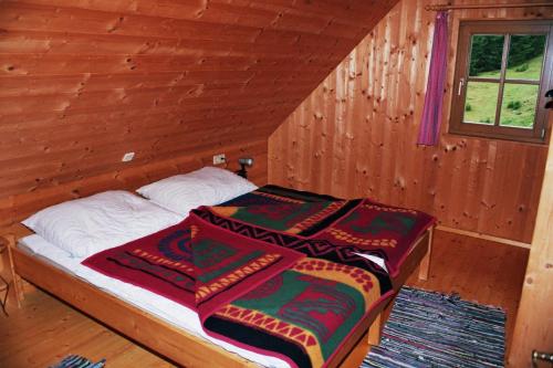 ein Schlafzimmer mit einem Bett in einer Holzhütte in der Unterkunft Bischofhütten in Bad Sankt Leonhard im Lavanttal