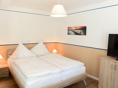 ein weißes Bett in einem Zimmer mit einem TV in der Unterkunft Studio apartment Wyk auf Föhr - DNS10103j-S in Wyk auf Föhr