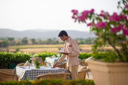a man is holding a plate at a table at Ramgarh Lodge, Jaipur – IHCL SeleQtions in Jaipur