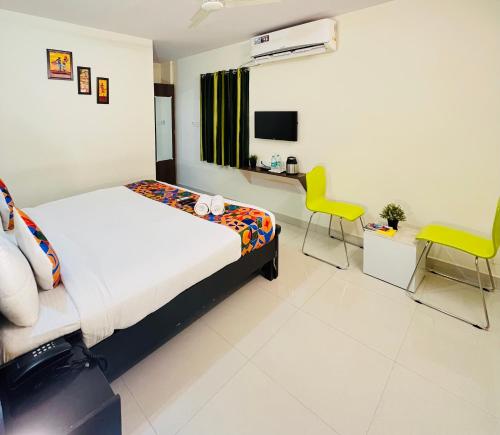 a bedroom with a bed and two yellow chairs at HOTEL NAMAHA in Shamshabad