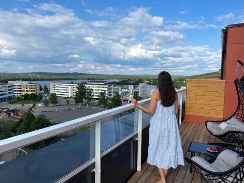 a woman in a white dress standing on a balcony at Penthouse in the city center in Rovaniemi