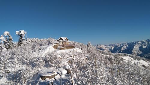 a cabin on the top of a snow covered mountain at Rai Desh Cottages in Shimla