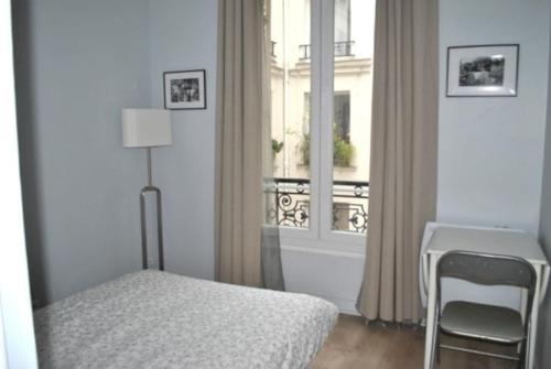 une chambre avec un lit, un bureau et une fenêtre dans l'établissement Appartement de 80 m² proche Gare du Nord, à Paris