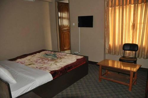 um quarto com uma cama, uma mesa e uma cadeira em International Hotel Appt em Kathmandu