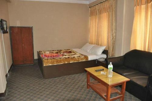 um quarto com uma cama, um sofá e uma mesa em International Hotel Appt em Kathmandu
