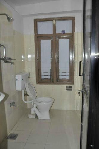 uma casa de banho com um WC, uma janela e um chuveiro em International Hotel Appt em Kathmandu