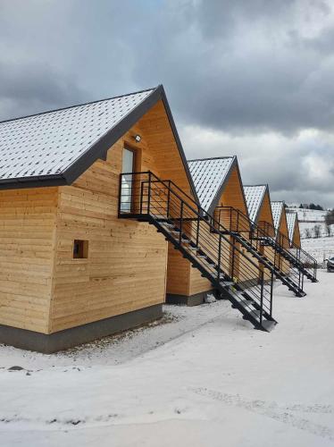 a row of wooden houses in the snow at Motylowe Wzgórze Apartamenty Zawóz in Zawóz