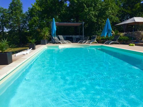 a large swimming pool with chairs and umbrellas at maison de campagne avec piscine in Béduer